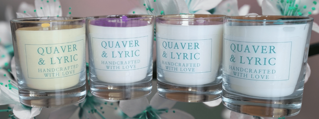 a group of four scented candles in glass containers with quaver qnd lyric branding